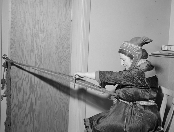 En samisk kvinne sitter og vever i Vitenskapsmuseet i Trondheim. Bildet er tatt i 1957. Foto: Schrøder-arkivet/Trøndelag Folkemuseum